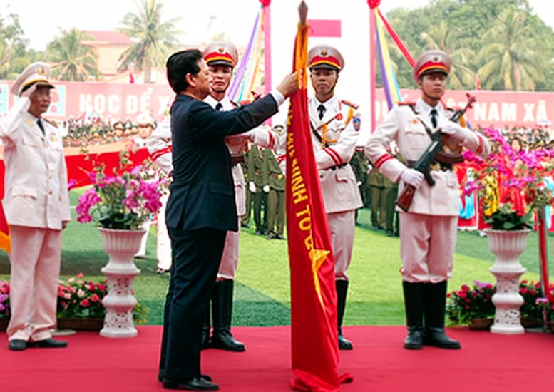 Thủ tướng Nguyễn Tấn Dũng gắn Huân chương Sao Vàng lên lá cờ truyền thống của Học viện An ninh nhân dân.Ảnh: Chinhphu.vn.